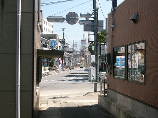 二つの建物の間から見える直線の道路。道の両脇はにぎわっている感じ。