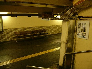 鈍いクリーム色の壁の角。右に行けば1・2番のりば。地面はアスファルトになっている。