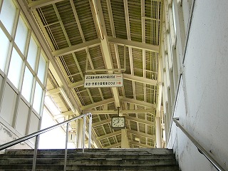 クリーム色の鉄骨に波板をのせた三角型上屋を階段から見上げる