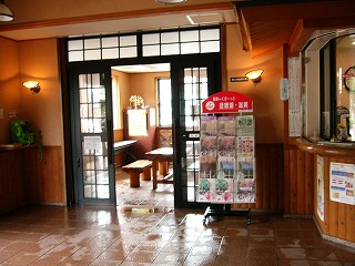 黒枠のサッシに嵌められたガラス戸が入り口両端にあり、扉だけ開けて通路を作っている。