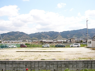 手前に広い空き地、少し遠くに痩せてなだらかで低い山地。