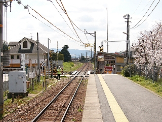 遠くで急にカーブしている単線とホームの先に見える簡易駅舎。