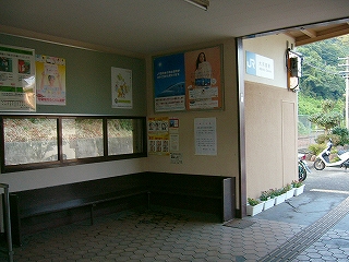 駅舎に入ってのすぐ右の様子。建物の角でかなり暗くて陰気な雰囲気。こげ茶の長椅子、その上に高さの低い窓、その上に何枚かのポスター、そして天井。