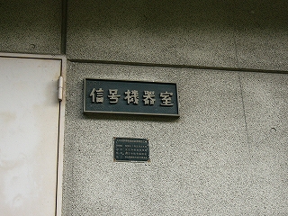 剥げた金色の枠と浮き出し文字で作られた黒地の厚いプレート。