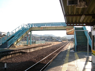 階段を両手に広げる黄色の桁と緑の柵の跨線橋。