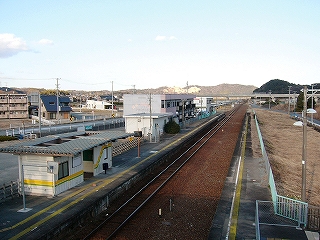 跨線橋から駅舎と線路内を見下ろして。ずっと左のほうには新しいアパートや戸建が並んでいるが、あいだに空き地が多い。