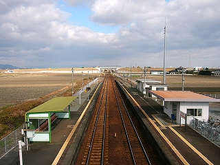 広がる休耕田の中まっすぐに伸びる線路とホーム。
