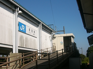 白いホームの外壁に沿った坂道の上に改札小屋がある。