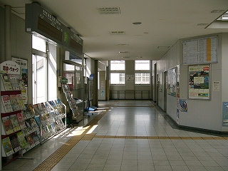 白いコンコース。窓から柔らかな光が差し込む。パンフレットの棚。