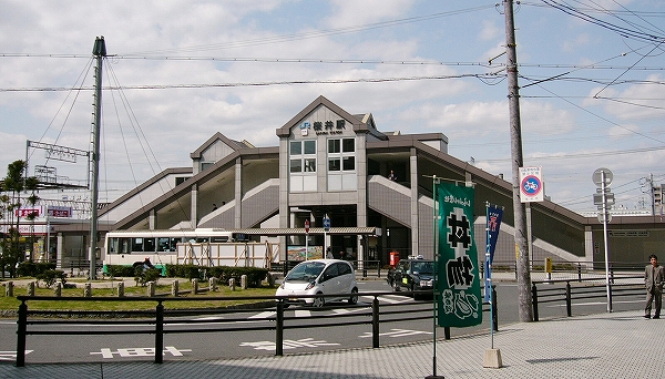 左右に階段の足を下ろした小さな三角屋根を持つタイル貼りの駅舎。