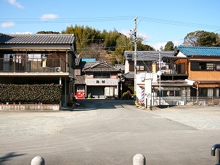アスファルトの駅前広場。目の前は一般的な住宅で、その列を抜けるようにＴ字路がある。