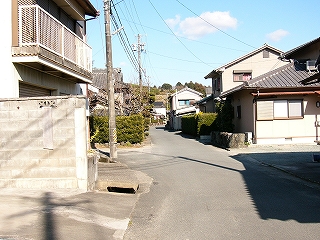 アスファルトの細道にさまざまな住宅が軒を連ねる。