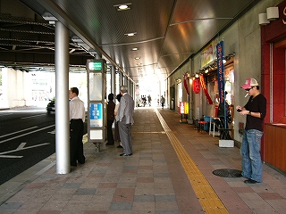 床に灰赤色のタイルを敷き、歩道上部の天井を少し下げて白くした高架下の風景。