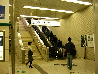 階段とエスカレーターの上り口前付近。あたりに太い柱がありすこし狭い感じがする。
