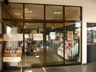 大きなサッシの引き戸4枚を連ねた食事処の入口。店内右手に長いカウンターがあり、左手はホームの窓に面していて、その横にテーブルと椅子がいくつか用意されている。