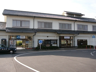 白色の壁の鉄筋コンクリート二階建て瓦葺の駅舎。お城風のデザインで、二階にあるすべての横長の窓には白い桟が縦に入れられている。