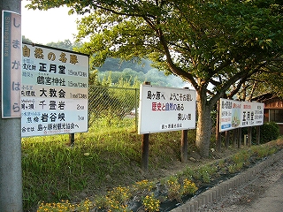 左の斜めに4つの立て看板を見て。看板の足元には黒ビニールで保護された穴のある花壇。