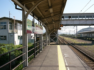 背後が簡単な柵になったホームからすぐ近くの建物が見える。