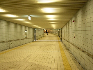 明るい灰色やベージュのタイルで覆われた地下道内。人はほとんどいない。