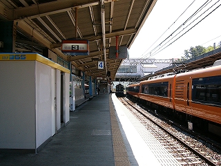 自販機の入ったボックスのあるホーム。隣の線路にはオレンジと青色の特急が停車している。