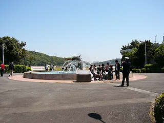 丸い噴水。グループの記念撮影をしている人たちがいる。