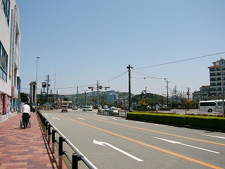 赤系統のタイルを埋め込んだ歩道と、三車線の道路。左手に鳥羽一番館の壁。