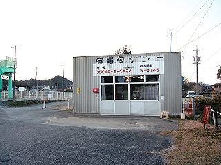 鼠色の波板とアルミサッシの引き戸の簡単な建物。