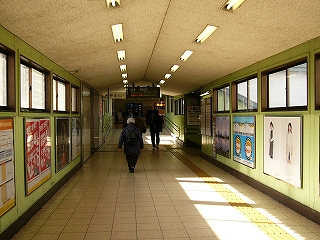 壁が薄みどりで天井が薄い三角の連絡通路。両脇の壁にはポスターが貼り並べられてある。