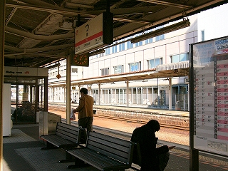 背中合わせになった焦げ茶の長椅子が二組、上方に電照式駅名標、右手に時刻表。