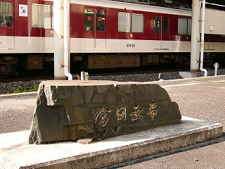 背景に近鉄の編成。手前に「今日無事」と彫られた背の低い横長の石。