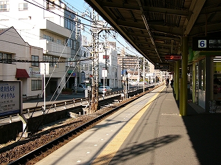 左手に駅の裏の風景。様々な高さで形の個人の低いビルが並び、通りは日が差し込んで明るい。