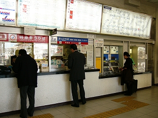 上部に電照式時刻表、路線図案無いが並び、下方に有人改札口が並ぶ。