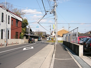 左に昔からの手狭な二車線の道。