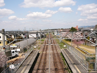 まっすぐ伸びる線路内。遠くに山は見えず、盆地が広がっている。