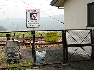 焦げ茶のフェンス。「構内立入禁止」や「通行禁止」と書かれた看板がある。