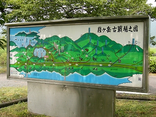 空を水色で、湖を水色の点描で表現し、濃い緑で山々を書いた案内図。赤と青で武将の攻めたルートが書かれている。また山々の上には、そこに陣取った武将の名前が書かれている。