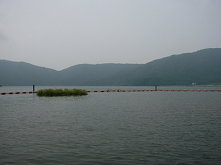薄曇の湖。少し遠くに灰緑の低い山がどんより鎮座している。