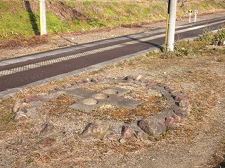 土のある緑地部に埋め込まれた十字のブロック。