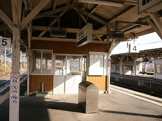 上屋下に作られた薄茶色の壁の待合室。扉はサッシの引き戸。