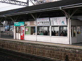 側面にサッシの窓がついた上屋下の待合室。窓の上には落ち着いた広告看板が取り付けられている。