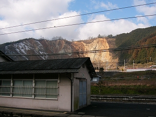 ホーム上のコンクリートの詰所と背景の荒々しい採石場。